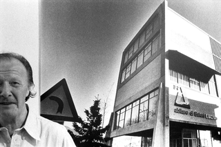 Designer e architetti, 064-064-14 L'architetto Belotti ritratto davanti a una fotografia della sede di Abitare Baleri ad Albino, da lui progettata, 1978 Albino (Italia)
